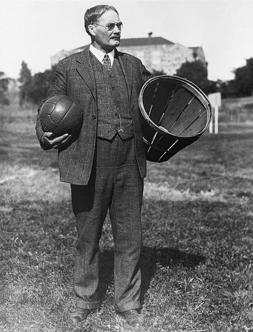 James Naismith avec le ballon et le panier dédiés au basketball, vers 1930.