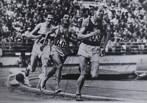 photo noir et blanc de 3 athlètes courant dans un stade olympique et un tombé au sol